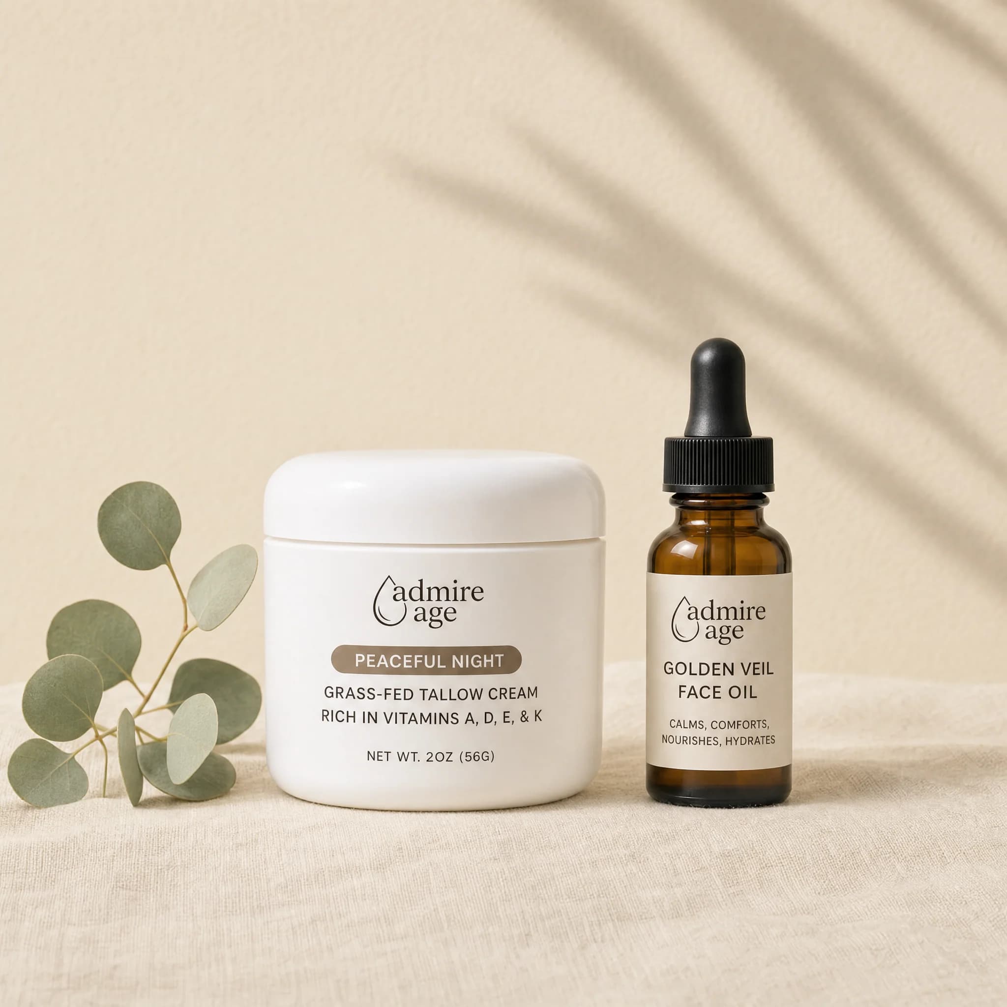 Peaceful Night Tallow Cream jar and Golden Veil Face Oil dropper bottle grouped together on a cream linen surface with a eucalyptus sprig