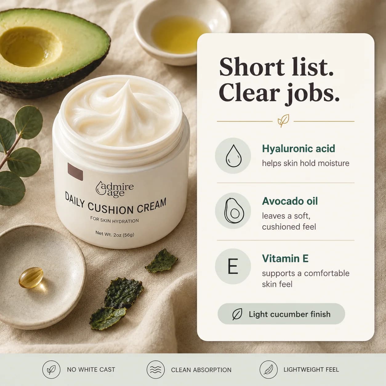Editorial ingredient still life: half a ripe avocado, eucalyptus, a kale leaf, and a gold vitamin E capsule on a ceramic saucer arranged around the Daily Cushion Cream jar; a card to the right titled 'Short list. Clear jobs.' lists hyaluronic acid, avocado oil, vitamin E, and a light cucumber finish