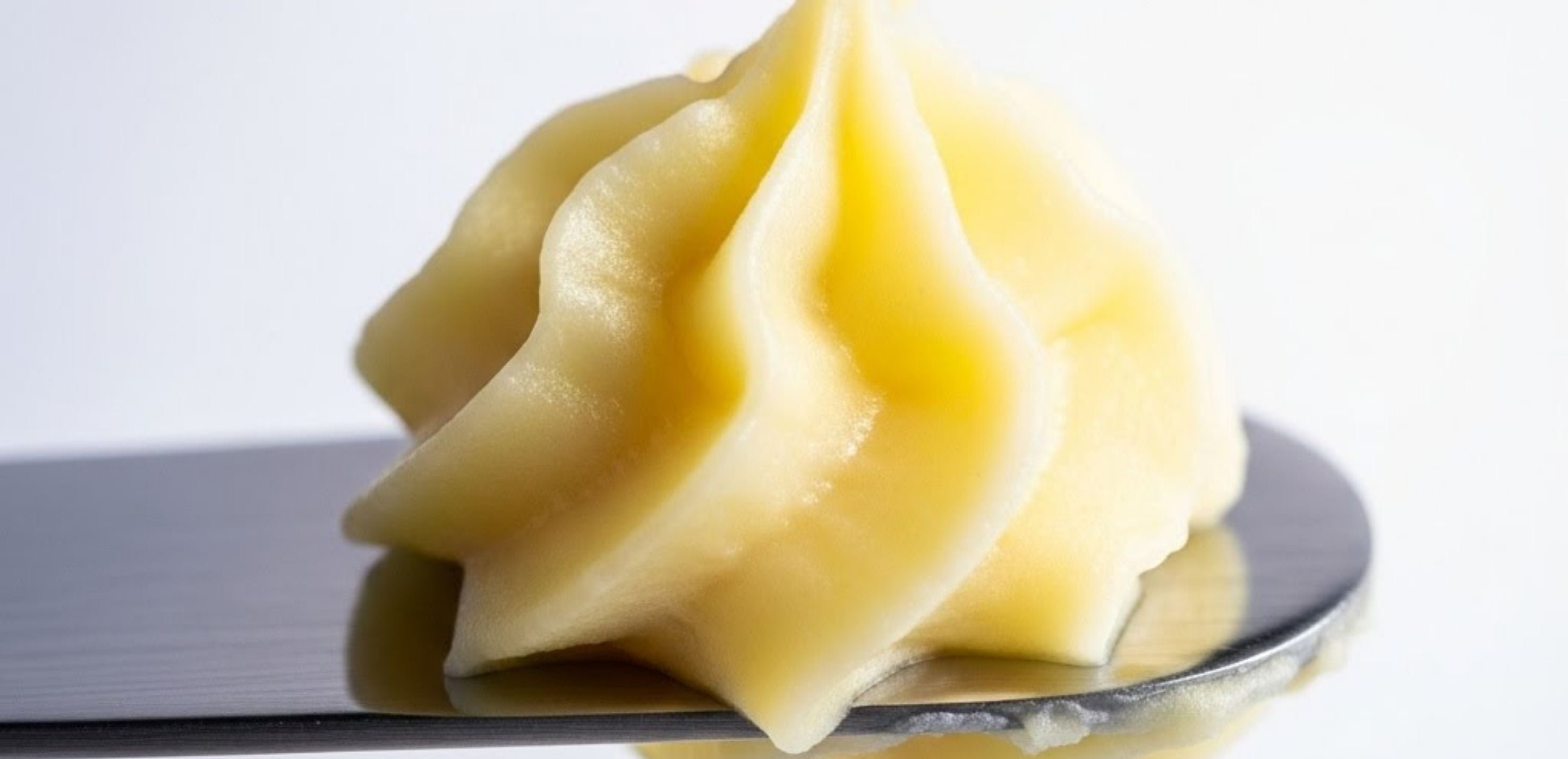 Close-up of whipped tallow balm with soft peaks on a spatula.
